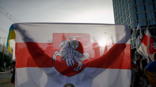 Женщина держит бело-красно-белый флаг во время участия в марше, посвященном Дню беларусской воинской славы. Варшава, Польша. 9 сентября 2023 года. Фото: Татьяна Веремеева / Белсат