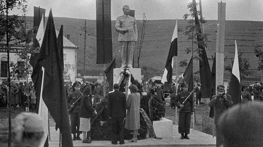 Ustrzyki Dolne w 1954 roku. Warta honorowa przed pomnikiem Józefa Stalina i delegacje z kwiatami. Z tyłu dawna synagoga, w tym czasie magazyn zbożowy. Fot. Tadeusz Ogonowski / Forum