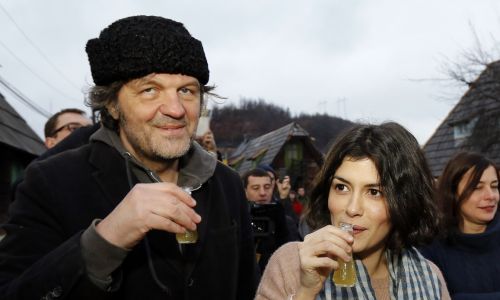Goście w gospodzie delektują się „rdzennie serbskimi” daniami, popijając je (Coca-Cola jest zakazana) śliwowicą lub sprowadzanymi z Kuby sokami owocowymi marki „Che”. Tu francuska aktorka Audrey Tautou pije lokalne ‘brandy’ z Emirem Kusturicą, 2013 r. w Drvengradzie. Fot. Srdjan Stevanovic/WireImage/Getty Images