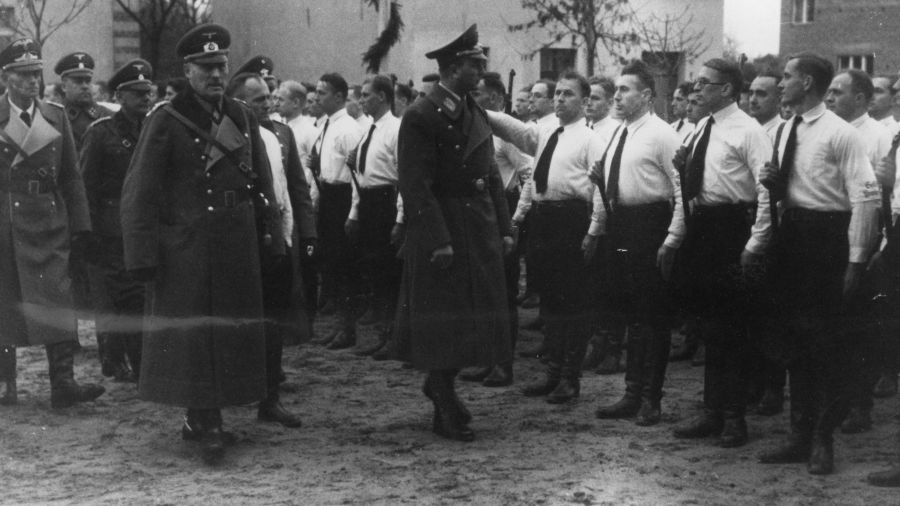 V kolumna często składała się z osób legalnie działających w II RP organizacjach mniejszości niemieckiej. Na zdjęciu: Uroczystość  „dnia wolności” w Środzie Wielkopolskiej obchodzonego 5 listopada 1939 roku z udziałem Artura Greisera, namiestnika Kraju Warty. Greiser przechodzi przed szpalerem organizacji paramilitarnej Selbstschutz. Fot. NAC